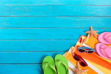 Beach scene with orange striped towel, starfish, sunglasses and flip flops on old blue wood decking.  Space for copy.の写真素材