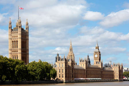 UK Houses of Parliament with blue fluffy sky and Union Jack flag flying in the wind.  Photo taken at an angled view from the south side of the River Thames.  Perspective corrected.の写真素材