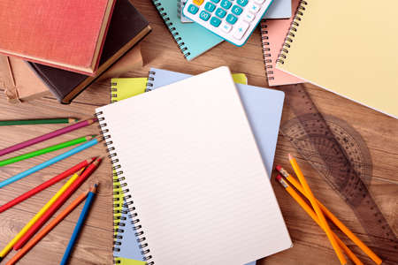 Student's desk with open notebook, text books, various pencils and calculator.の写真素材