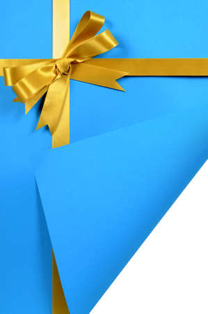 Gold gift ribbon on blue paper background with curled corner.の写真素材