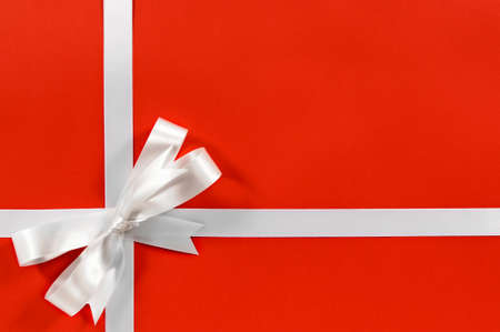 Christmas border frame gift ribbon in white satin on red paper background horizontalの写真素材