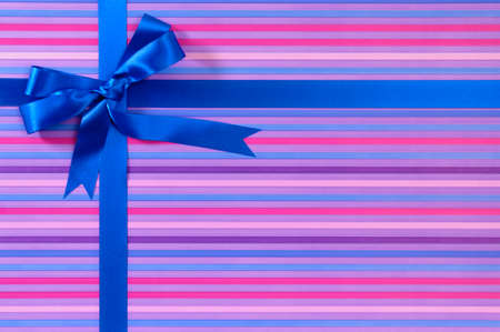 Blue Christmas or birthday gift ribbon bow on candy stripe wrapping paper backgroundの写真素材