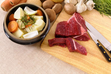 Preparing beef for casserole or stew with ingredients and knife on kitchen chopping board.の写真素材