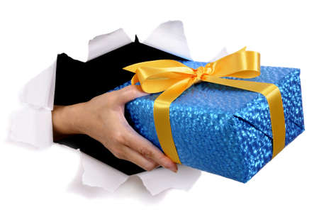 Man hand delivering or giving gift through torn white paper backgroundの写真素材