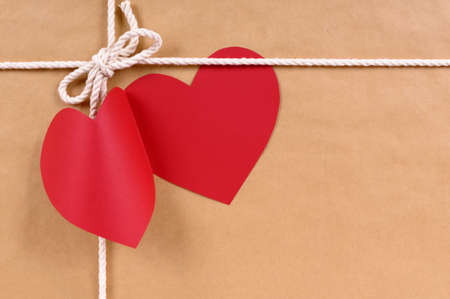 Valentines day red heart shape gift tag, brown paper package parcel background, copy spaceの写真素材