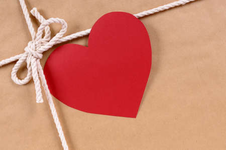 Valentine gift with red heart shape gift tag, brown paper package parcel background, copy spaceの写真素材