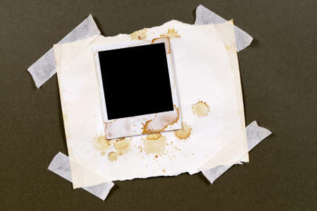 Old vintage stained polaroid style blank photo print frame taped to torn parchment paper backgroundの写真素材