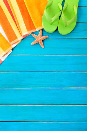 Summer beach objects border, flip flops, copy space, vertical, blue background