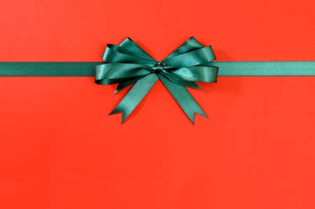Green gift ribbon bow straight horizontal red paper backgroundの写真素材