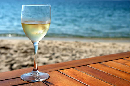 Glass of white wine on mediterranean beach tableの写真素材