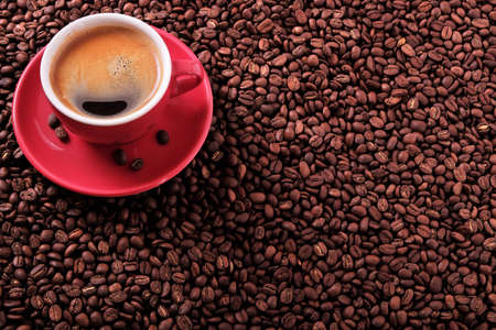 Red coffee cup with espresso and roasted beans background