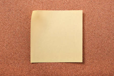 Yellow sticky post note on cork board