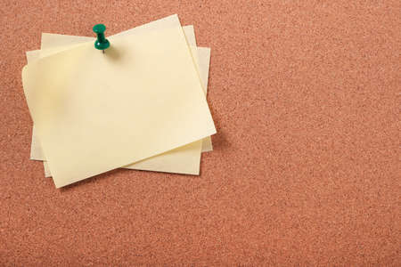 Several yellow sticky post notes pinned pushpin cork boardの写真素材