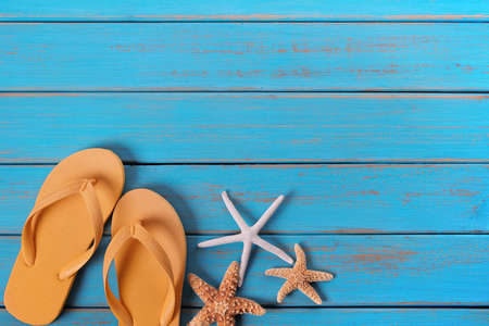 Flip flops star fish summer seashore blue wood backgroundの写真素材