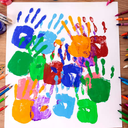 Painted handprints with art and craft equipment on a school table.の写真素材