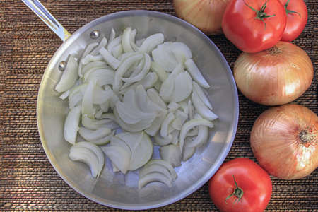 Chopped Onions in Frying Pan with Unpeeled Onions and Tomatoesの写真素材