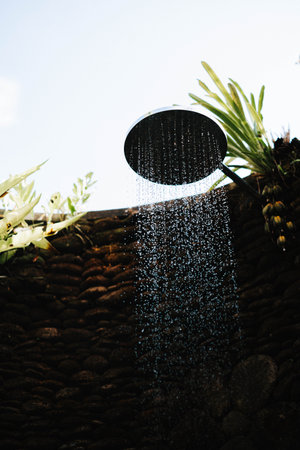 Outdoor shower that surrounded by wall that made from authentic river stone and some fernsの写真素材