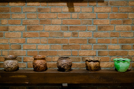 Mini jars made of brown clay as decoration on a wooden shelfの写真素材