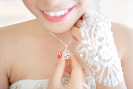 Hi-res photo of an unrecognized asian wedding bride is smiling while holding diamond necklace with narrow depth-of-fieldの写真素材