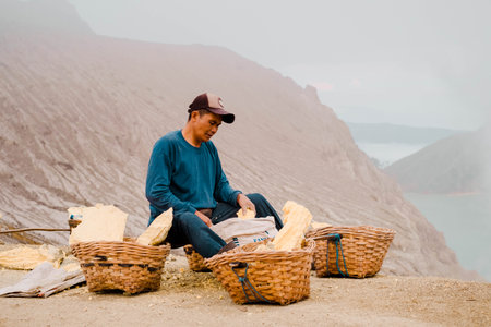 Sulphur miner sculpting lumps of sulphur or brimstone into small statue as local souvenirのeditorial素材