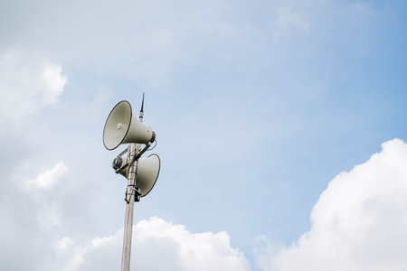 White megaphones mounted on poles in outdoor against blue sky backgroundの写真素材