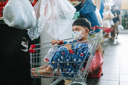 An Indonesian kid is sitting on the shopping cartのeditorial素材