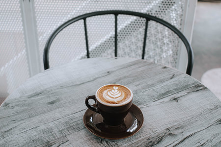 A cup of coffee with latte art on a wooden table. Blurred background.の写真素材