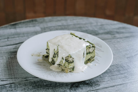 A plate of Japanese Matcha Cake with Creamy Custard on a wooden table. Blurred backgroundの写真素材