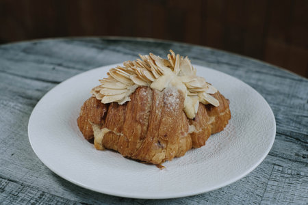 Close-up Shot of a Plate of a Croissant with Almond Topping. Blurred Background.の写真素材