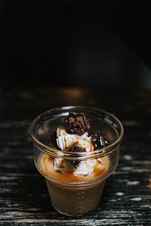 Portrait or vertical shot of a glass of ice cream with coffee and additional brownies cake. Blurred background.の写真素材