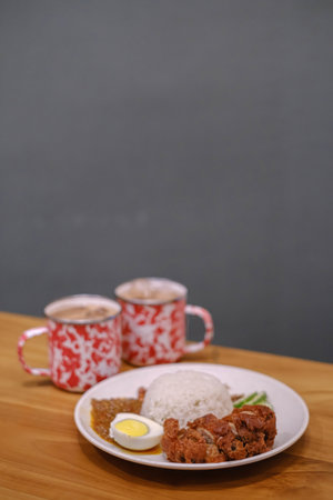 Portrait or vertical shot of a plate of Nasi Lemak with two mugs of tea. Blurred background.の写真素材