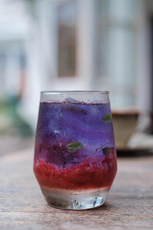 Vertical shot of a fresh drink made of Strawberry Fruit combined with Blue Tea made of Clitoria Ternatea usually known as Butterfly Pea Flower on a wooden table. Bokeh or blurred background.の写真素材