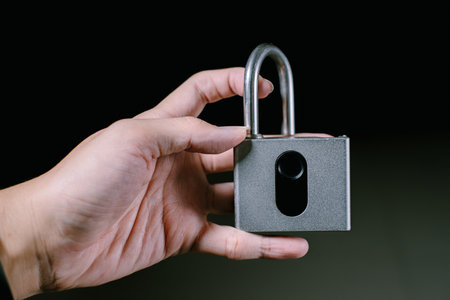 A hand is holding a unlocked fingerprint padlock. Isolated black background. Suitable for advertisement.の写真素材
