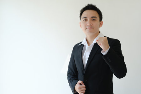 Young Asian businessman with flat face expression clenching his fist and looking to the camera. Isolated white background.の写真素材