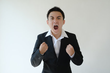 Young Asian business man with excited face expression and looking to the camera. Isolated white background.の写真素材