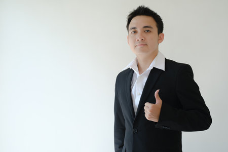 Young Asian boss giving thumbs up to the camera. Isolated white background.の写真素材
