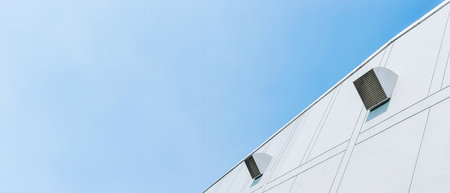 White industrial building with small vents against clear blue sky. Minimalist architecture.の写真素材