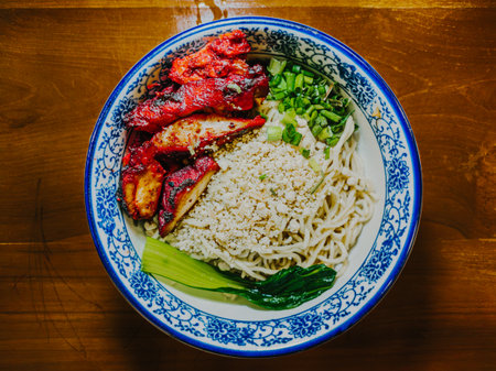 Chinese noodles filled with red pork meat and vegetables on a traditional porcelain bowl. Flat lay or top view.の写真素材