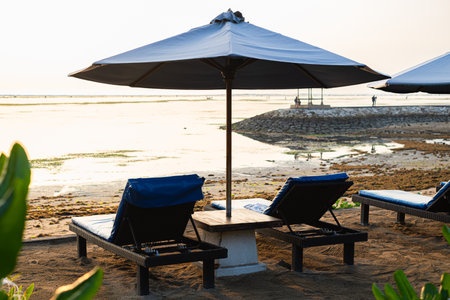 Beachfront with blue lounge chairs over sunset. Bokeh background.