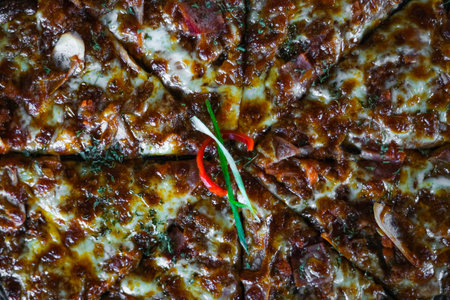 Pizza with golden-brown crust and dark texture surface, melted cheese, a single red chili pepper and...