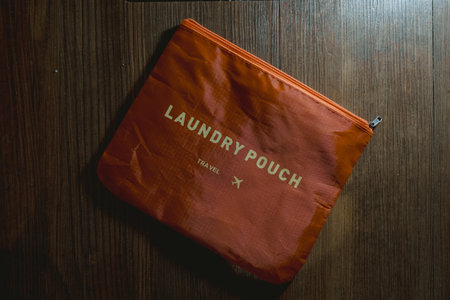 Orange laundry pouch on the wooden floor for travel with flay lay angle