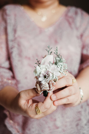 Close-up shot of the hand of a woman holding a corsage with bokeh background