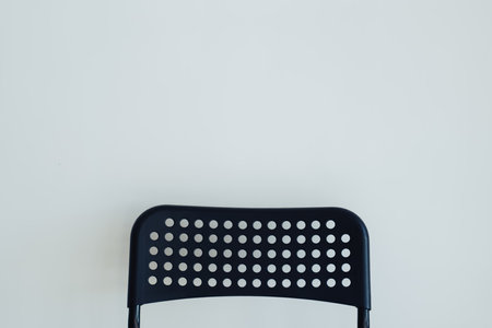 A minimalist single black chair against white wall as backgroundの写真素材