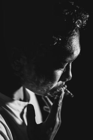 Young Southeast Asian man smoking in black and white with bokeh. Close-up fine art.の写真素材