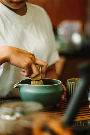 Hands whisking hojicha in an indoor setting, capturing the calming ritual of authentic tea preparation.の写真素材