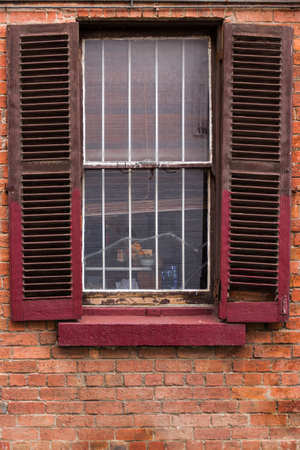 Open window shutters on an old, crumbling building.