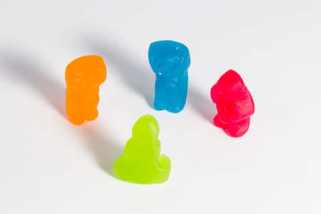 Red, blue, orange and green jelly babies in discussion, on a white background.の写真素材