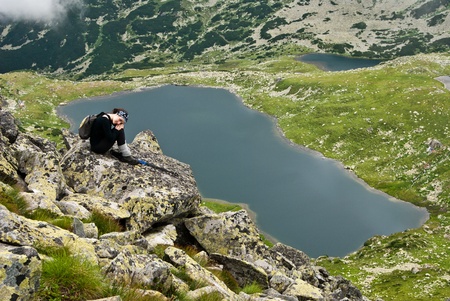 Hiker girl in Retezat mountain,siting on a rock above Bucura lakeの写真素材