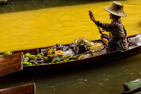 Ratchaburi Province. Thailand - January 02, 2014: Fuit vendors sell their product at the well-known Damnoen Saduk floating market near Bangkok. This famous market becomes a hive of colourful activity in the mornings.のeditorial素材