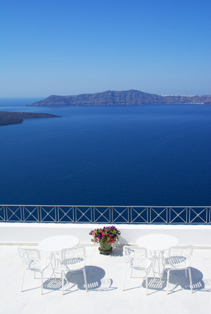 Stunning outdoor seating at the terrace over the caldera on vibrant blue Aegean sea, Santorini islandの写真素材